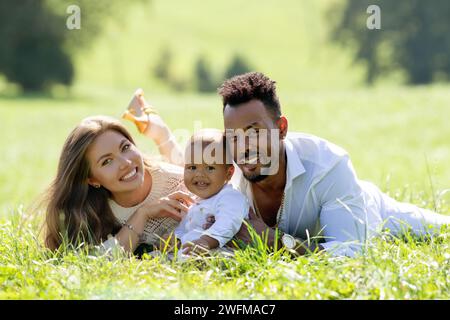 Parents multiethniques et bébé de race mixte dans le parc. Portrait multiethnique de famille en plein air. Bébé biracial sur la cour. Famille multiethnique diversifiée Banque D'Images