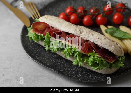 Délicieux sandwich avec bresaola servi sur une table gris clair, gros plan Banque D'Images