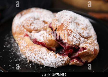 Délicieux petits pains avec des baies et de la poudre de sucre sur l'assiette, gros plan Banque D'Images