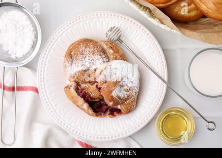 Délicieux petits pains avec de la poudre de sucre et des baies sur une table carrelée blanche, mise à plat Banque D'Images