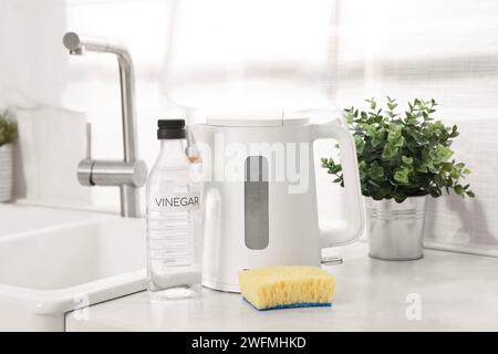 Nettoyage de la bouilloire électrique. Bouteille de vinaigre et éponge sur le comptoir dans la cuisine Banque D'Images