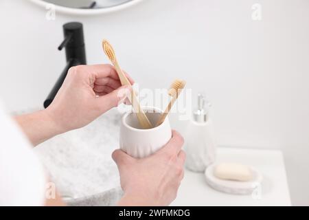 Accessoires de bain. Femme avec brosses à dents dans le support en céramique à l'intérieur, gros plan et espace pour le texte Banque D'Images