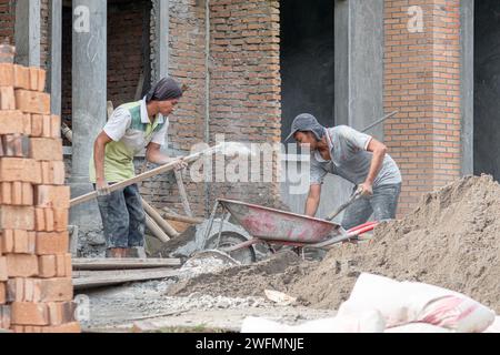 Les ouvriers asiatiques de la construction font leurs travaux le matin. Construction de maisons résidentielles. Banque D'Images