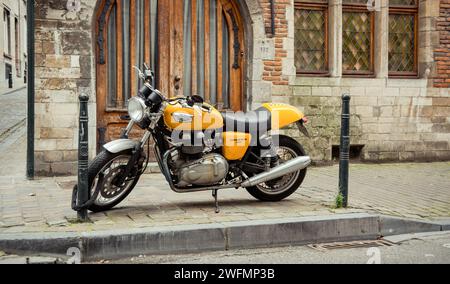 Triumph Thruxton 900 garé sur le trottoir. Moto jaune de style classique dans la rue du centre de Bruxelles. Banque D'Images