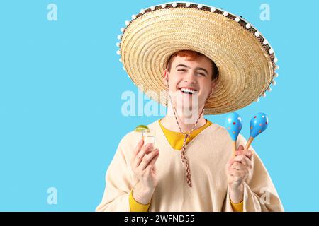 Portrait d'un jeune Mexicain en sombrero, avec tequila et maracas sur fond bleu Banque D'Images