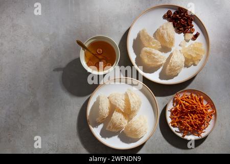 Un plat de nid d'oiseau comestible et de jujujube décoré de cordyceps et un bol en céramique contenant de la soupe de nid d'oiseau. Espace de copie. Concept de santé Banque D'Images