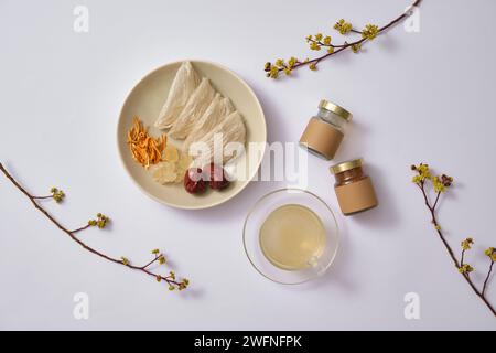 Une tasse de soupe de nid d’oiseau, des bocaux en verre avec étiquette vide et un plat de nid d’oiseau comestible, cordyceps, sucre de roche et jujube. Combinaison saine pour l'homme Banque D'Images