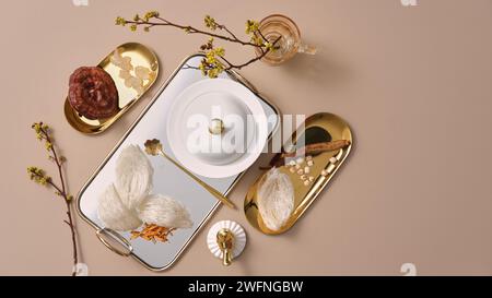 Un plateau avec cloche en porcelaine posée sur un plat et nid d’oiseau comestible et cordyceps, plat doré avec champignon lingzhi et ginseng. Le valu nutritif Banque D'Images