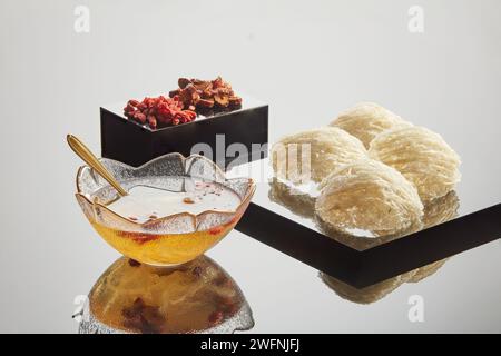 Podiums de forme géométrique avec nid d’oiseau comestible, jujube et baies de goji séchées placés dessus. Un bol transparent de soupe de nid d’oiseau à côté. Bird’s ne Banque D'Images