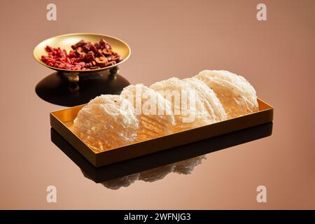 Nid d’oiseau comestible placé sur un plat doré décoré d’un plat de jujube et de baies de goji séchées. La santé et l'état de la peau peuvent être améliorés en mangeant Banque D'Images