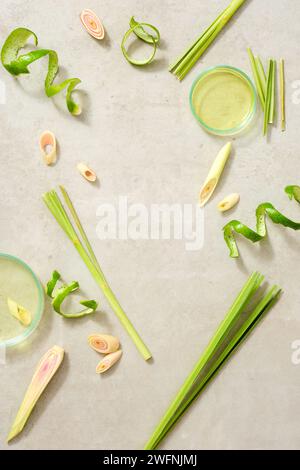 Quelques boîtes de Pétri d'huile essentielle extraite de citronnelle ornées d'écorces de citron et de citronnelle sur fond clair. Espace vide pour le produit p Banque D'Images
