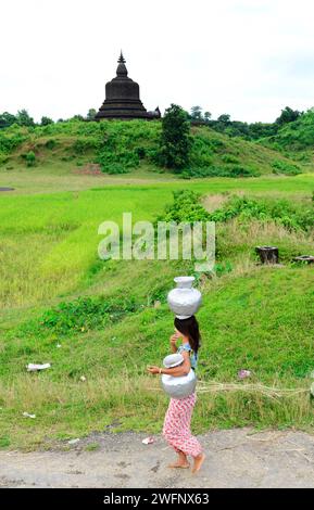 Une femme arakanaise transportant des cruches d'eau dans leur village de Mrauk-U dans l'État de Rakhine, Myanmar. Banque D'Images