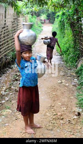 De jeunes filles arakanaises transportant des cruches à eau dans leur village de Mrauk-U dans l’État de Rakhine, au Myanmar. Banque D'Images