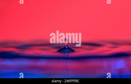 Une goutte d'eau tombe sur une surface colorée. Banque D'Images
