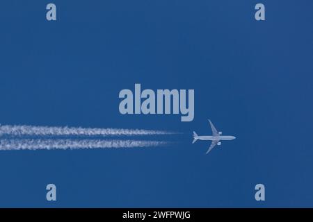 Dessous d'un Boeing 777-300 reg F-GSCB d'Air France volant à haute altitude 37 000 pieds de Paris à Los Angeles dans un ciel bleu clair avec des traînées Banque D'Images