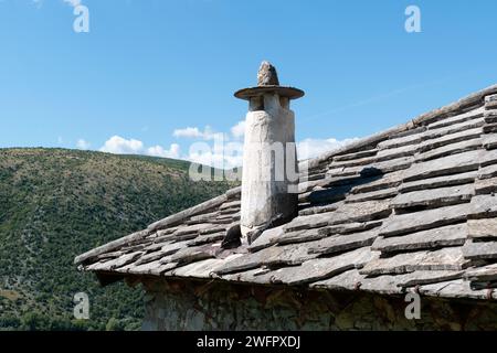 Tuiles de toit en pierre et cheminée sur la maison médiévale traditionnelle dans la vieille ville de Pocitelj, Bosnie-Herzégovine, contre le ciel bleu Banque D'Images