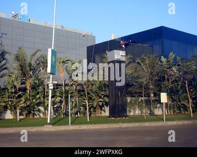 Le Caire, Egypte, janvier 23 2024 : entretien et nettoyage de l'extérieur d'un bâtiment, nettoyage du verre par des ouvriers sur des fils pour donner le service de nettoyage par Banque D'Images