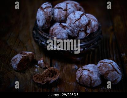 Biscuits froissés au chocolat avec du sucre en poudre dans un vase en bois. Biscuits au chocolat craquelés sur bois. tableau. Banque D'Images