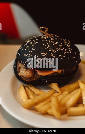 Frites et un hamburger de bœuf avec un pain noir dans un café. Délicieux déjeuner américain Banque D'Images