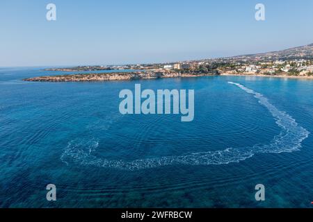 Bateau flottant dans l'eau de mer de Chypre près de la plage de sable fin. Voyages d'été et stations balnéaires méditerranéennes. Banque D'Images