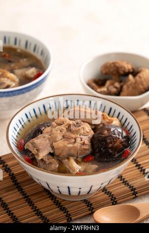 Délicieuse soupe de poulet aux champignons shiitake take taïwanais dans un bol sur fond de table blanc. Banque D'Images