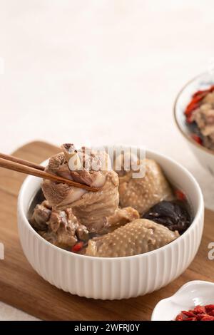 Délicieuse soupe de poulet aux champignons shiitake take taïwanais dans un bol sur fond de table blanc. Banque D'Images