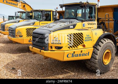 Machinerie lourde, tombereaux et excavatrices stationnés sur Hythe Beach prêts pour le réapprovisionnement des défenses marines Banque D'Images