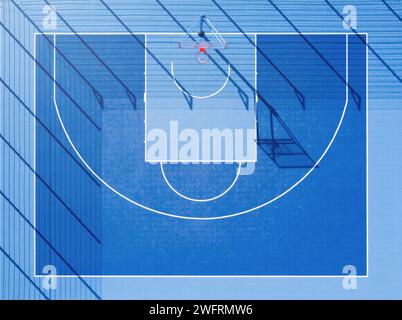 Vue de dessus du terrain de basket-ball. Une cour bleue minimaliste avec de longues ombres en plein jour de vue aérienne. Banque D'Images