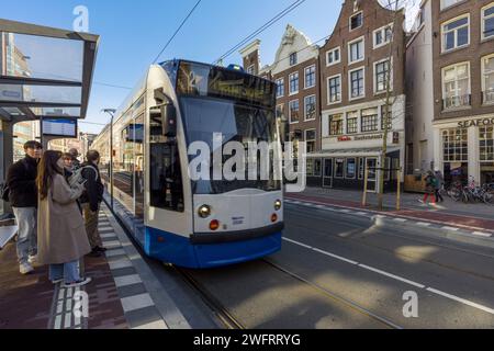 Personnes attendant un tram à Nieuwezijds Voorburgwal dans le centre d'Amsterdam, Hollande du Nord, pays-Bas. Banque D'Images