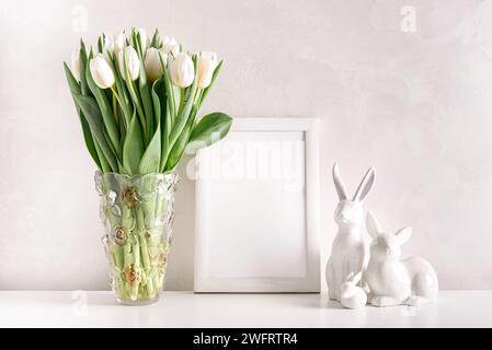 Bordure en bois vierge avec des figurines de lapins de Pâques et bouquet de tulipes blanches sur fond blanc. Concept de célébration de Pâques. Espace de copie. Vue avant Banque D'Images