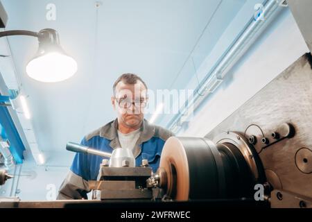 turner âgé, 50-55 ans, travaille au tour dans l'atelier de tournage. Vue avant. Flux de travail authentique. Banque D'Images