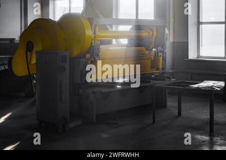 Type de machine industrielle pour couper des tôles de fer ou de métal. Guillotine stands dans l'atelier de production à l'usine. Lumière à travers les fenêtres. Équipement industriel. Métal laminé. Banque D'Images