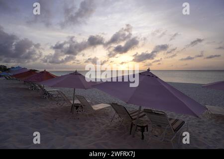 Un coucher de soleil sur Shoal Bay East à Anguilla avec de nombreux parapluies Banque D'Images