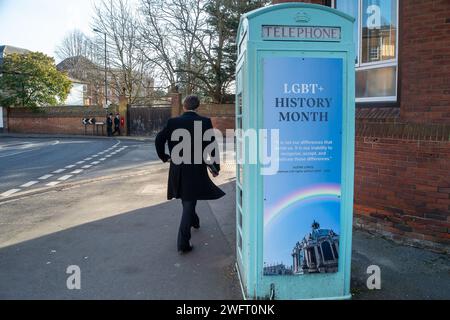 Eton, Windsor, Royaume-Uni. 1 février 2024. Un garçon de l'Eton College passe devant une ancienne cabine téléphonique de la bibliothèque communautaire à l'extérieur de la célèbre école publique de l'Eton College avec une bannière marquant le mois de l'histoire LGBT+ qui commence aujourd'hui. Le directeur du Eton College, Simon Henderson, surnommé «Trendy Hendy», a précédemment déclaré qu'il était «réveillé» sans répit. L'année dernière, il a créé un nouveau rôle de « directeur de l'éducation à l'inclusion » pour superviser les efforts de diversité à l'école. Crédit : Maureen McLean/Alamy Live News Banque D'Images