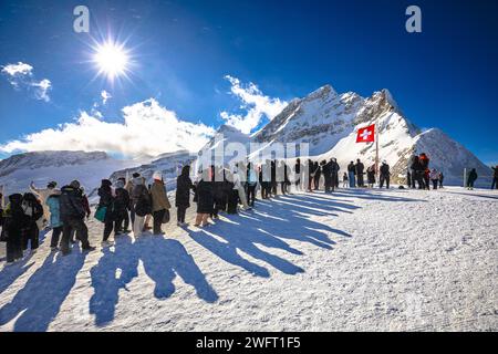 Les touristes attendent dans la file pour prendre une photo devant le drapeau suisse sur le pic Jungfraujoch, région Berner Oberland en Suisse Banque D'Images