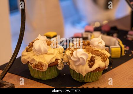 Une paire de cupcakes au café et aux noix faits maison recouverts d'un glaçage crémeux au beurre de café, de morceaux de noix et de meringues miniatures Banque D'Images