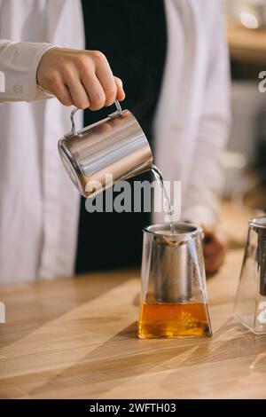 Un jeune barista prépare de délicieux thés dans un café moderne. Banque D'Images