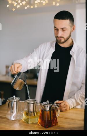 Un jeune barista prépare de délicieux thés dans un café moderne. Banque D'Images