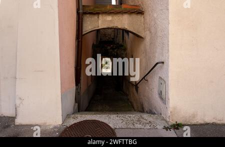 Passage ancien et sombre entre deux maisons à Aarau. Escaliers avec main courante métallique menant vers le bas. Existe peut être vu dans la distance. Banque D'Images