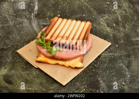 Les toasts cuits avec du fromage et de la saucisse reposent sur un fond sombre. Banque D'Images