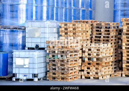 Une pile de conteneurs de fret en rangées à l'usine avec du liquide à l'intérieur et des palettes empilées Banque D'Images