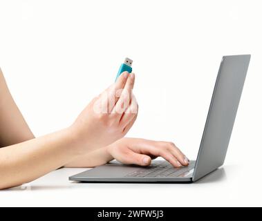 Photo recadrée d'une femme méconnaissable mains sur un ordinateur portable avec une clé USB sur une table de bureau dans un fond blanc isolé Banque D'Images