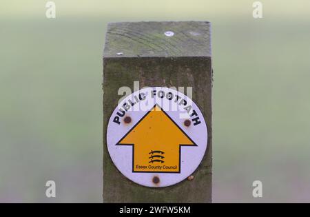Poteau en bois avec un panneau circulaire indiquant la direction d'un sentier public, tout droit, marqué par une flèche pointant vers le haut Banque D'Images