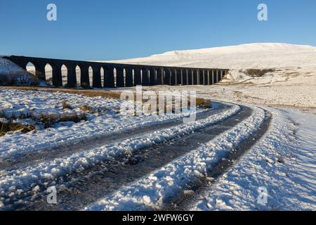 Le viaduc Ribblehead un jour d'hiver dans les Yorkshire Dales en Angleterre, avec Whernside couvert de neige en arrière-plan. Prise par une journée ensoleillée. Banque D'Images