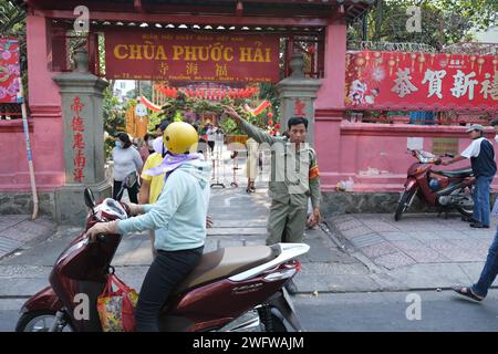 Le gardien de parking agite l'homme sur scooter loin de l'entrée de la pagode de l'empereur de Jade à Ho Chi Minh ville, Vietnam Banque D'Images