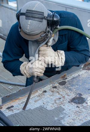 240123-N-UF592-1055 YOKOSUKA, Japon (23 janvier 2024) Aviation Boatswain’s Mate (gestion des avions) le recruteur de l’aviateur Rodney Pierce, d’Omak, Washington, utilise un ciseau pour enlever les matériaux antidérapants sur le pont d’envol du seul porte-avions déployé à l’avant de la marine américaine, USS Ronald Reagan (CVN 76), tandis qu’il est commandant au port, Yokosuka, en janvier 23. Ronald Reagan, le navire amiral du Carrier Strike Group 5, fournit une force prête au combat qui protège et défend les États-Unis, et soutient les alliances, les partenariats et les intérêts maritimes collectifs dans la région Indo-Pacifique. Banque D'Images