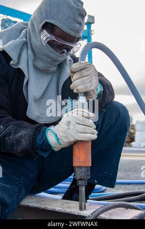 240123-N-UF592-1039 YOKOSUKA, Japon (23 janvier 2024) Aviation Boatswain’s Mate (gestion des avions) Airman Recruit Derrick Yaotse, de Hollywood, Floride, contrôle la corrosion en utilisant une ponceuse pneumatique sur le pont d'envol du seul porte-avions déployé à l'avant de l'US Navy, USS Ronald Reagan (CVN 76), tandis que Yokosuka, commandant au port, janv. 23. Ronald Reagan, le navire amiral du Carrier Strike Group 5, fournit une force prête au combat qui protège et défend les États-Unis, et soutient les alliances, les partenariats et les intérêts maritimes collectifs dans l'Indo-Pacifique Banque D'Images