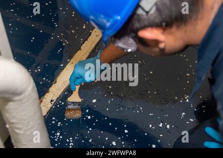 YOKOSUKA, Japon (10 janvier 2024) Aviation Boatswain’s Mate (équipement de lancement et de récupération) l’aviateur Christian Lazaro, de Chicago, applique une couche d’époxy transparent tout en appliquant un composé polyrésine sur le pont à bord du seul porte-avions déployé à l’avant de l’US Navy, l’USS Ronald Reagan (CVN 76), alors qu’il était au port Commander, Fleet Yokosuka, Fleet, Fleet Yokosuka, janvier 10. Ronald Reagan, le navire amiral du Carrier Strike Group 5, fournit une force prête au combat qui protège et défend les États-Unis, et soutient les alliances, les partenariats et les intérêts maritimes collectifs dans la région Indo-Pacifique. Banque D'Images