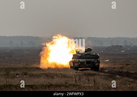 Soldats de l'armée américaine de la compagnie Alpha, 2e bataillon, 69e régiment blindé, équipe de combat de la 2e brigade blindée, 3e division d'infanterie, tirs d'un char M1A2 Abrams lors d'un exercice de tir réel dans la zone d'entraînement de Bemowo Piskie, Pologne, le 31 janvier 2024. La mission de la 3e Division d’infanterie en Europe est de s’engager dans des entraînements et des exercices multinationaux à travers le continent, en travaillant aux côtés des alliés de l’OTAN et des partenaires de sécurité régionaux pour fournir des forces crédibles au combat au V corps, le corps avancé déployé des États-Unis en Europe. Banque D'Images