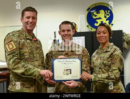 Colonel Ryan Garlow de l'US Air Force, à gauche, commandant de la 100th Air ravitaillement Wing, et le sergent-chef Tiffany Griego, à droite, chef de commandement de la 100e ARW, félicitent le sergent-chef Brandon Kapp, gestionnaire du déploiement de l’unité du 100e Escadron de maintenance, pour avoir été l’aviateur prêt de la semaine à la Royal Air Force Mildenhall, en Angleterre, le 18 janvier 2024. Les gestionnaires de déploiement d’unité sont affectés à une unité pour aider à suivre l’instruction et l’état de préparation médicale de leurs aviateurs. Banque D'Images